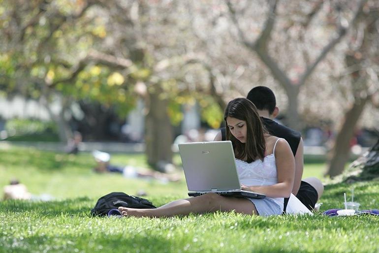 two students sit back to back while they study on the mounds