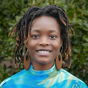 Taeya Boi-Doku ’24 has shoulder-length black hair in locs and wears brown hoop earrings and a blue and green top.